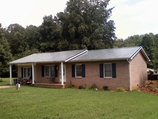Gray metal roof on a brick ranch house with a side carport in Washington